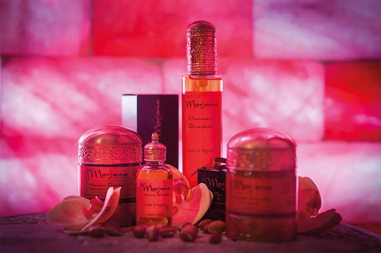 Flaconi di profumo e oli disposti su una parete di sale rosa illuminata
