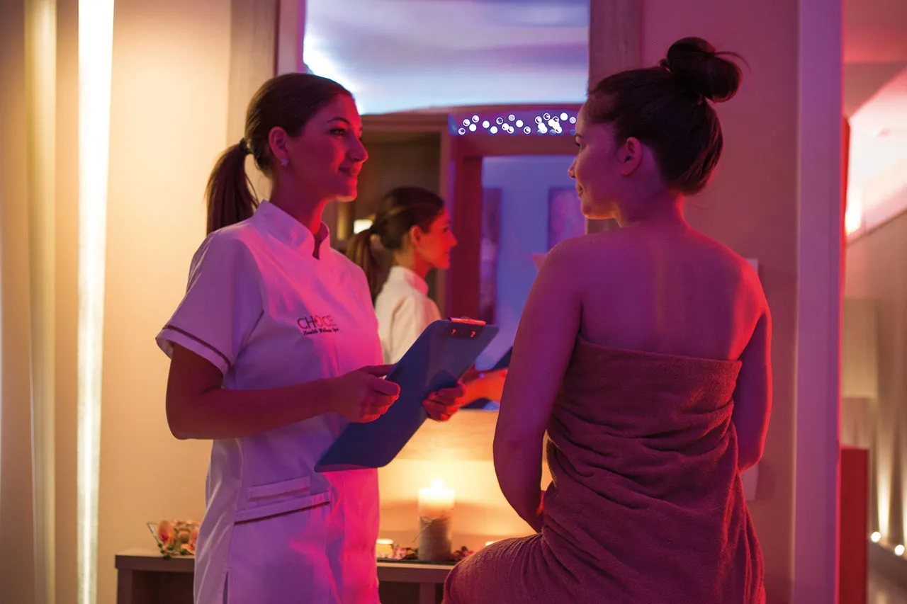 Una terapista Choice accoglie un’ospite nella spa, in luce calda